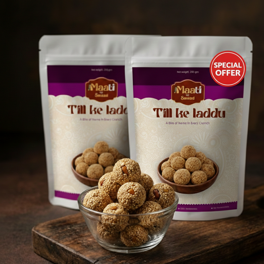 Two packages of Maati Sweet Till ke laddu with a bowl of laddu on a wooden surface.